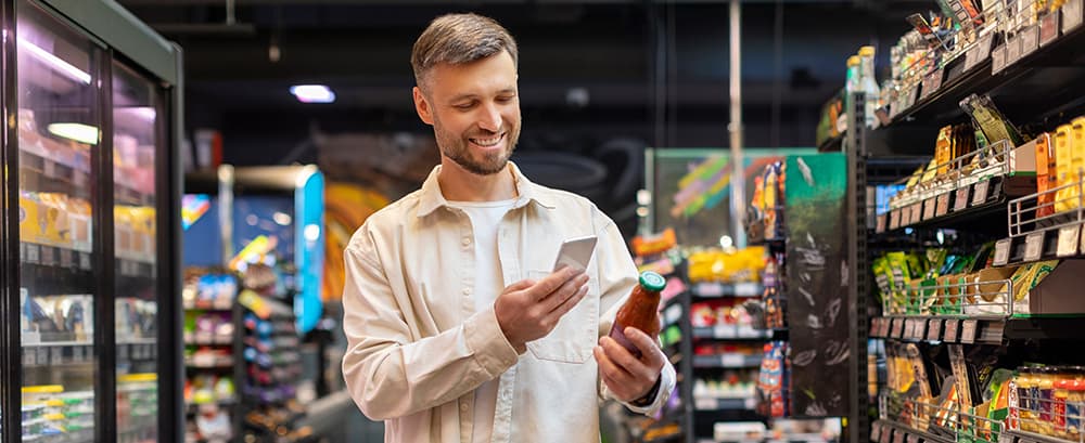 man in a grocery store scanning a UPC with his phone on a custom product label