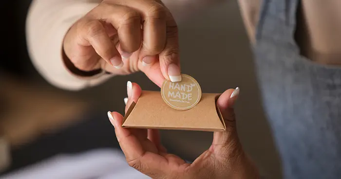 hand applying a handmade label to a package
